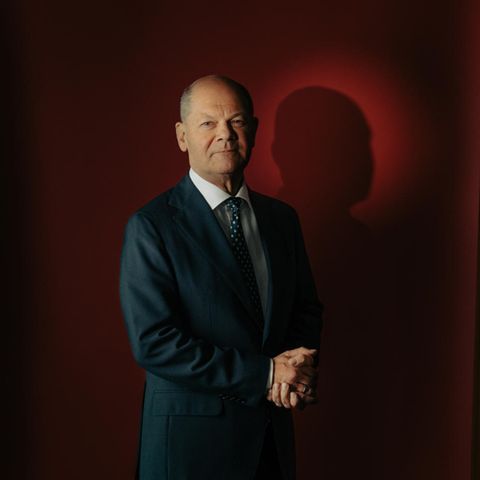 Portrait von Olaf Scholz vor rotem Hintergrund mit gefalteten Händen