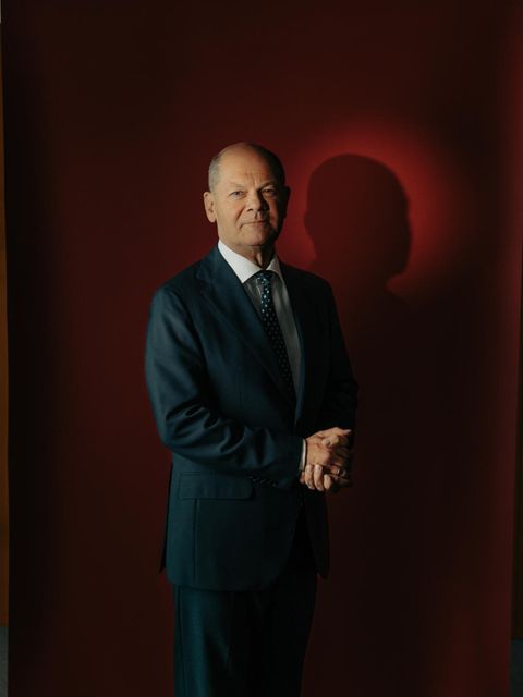 Portrait von Olaf Scholz vor rotem Hintergrund mit gefalteten Händen