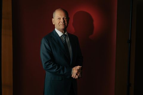 Portrait von Olaf Scholz vor rotem Hintergrund mit gefalteten Händen