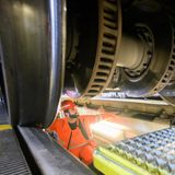 Bahn-Facharbeiter steht unter einem ICE und prüft die Räder