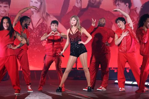 Taylor Swift und ihre Tänzer stehen auf einer in Rot gehüllten Bühne
