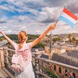 Eine Frau jubelt mit einer fahne Luxemburgs in der Hand