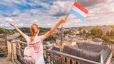 Eine Frau jubelt mit einer fahne Luxemburgs in der Hand