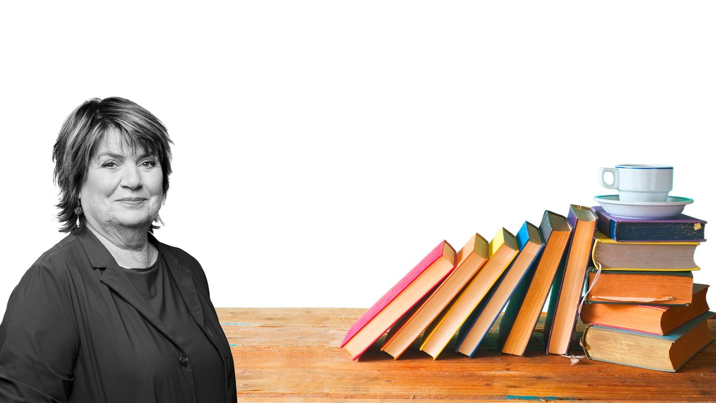 Westermann liest Frau Westermann vor einem Bücherstapel