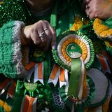 Eine Frau trägt Schleifen und einen Wollpullover in den Farben Orange, Grün und Weiß