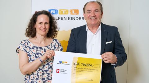 Vertreter der RTL- und stern-Stiftung halten einen Scheck über 750.000 Euro