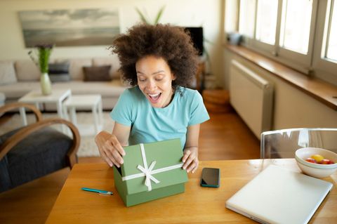Geschenkideen für Kreative: Eine Frau packt ein Präsent aus.