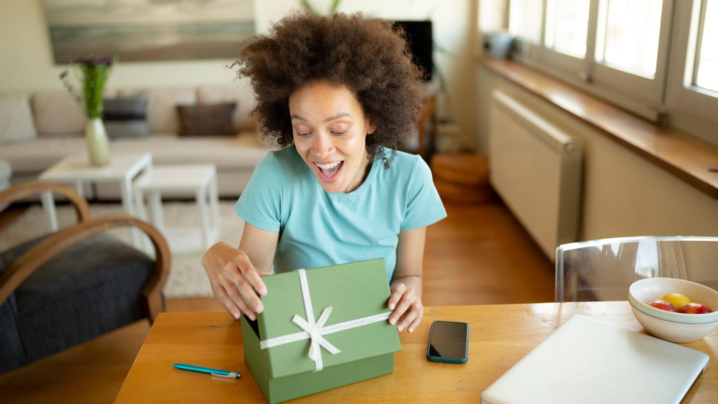 Geschenkideen für Kreative: Eine Frau packt ein Präsent aus.