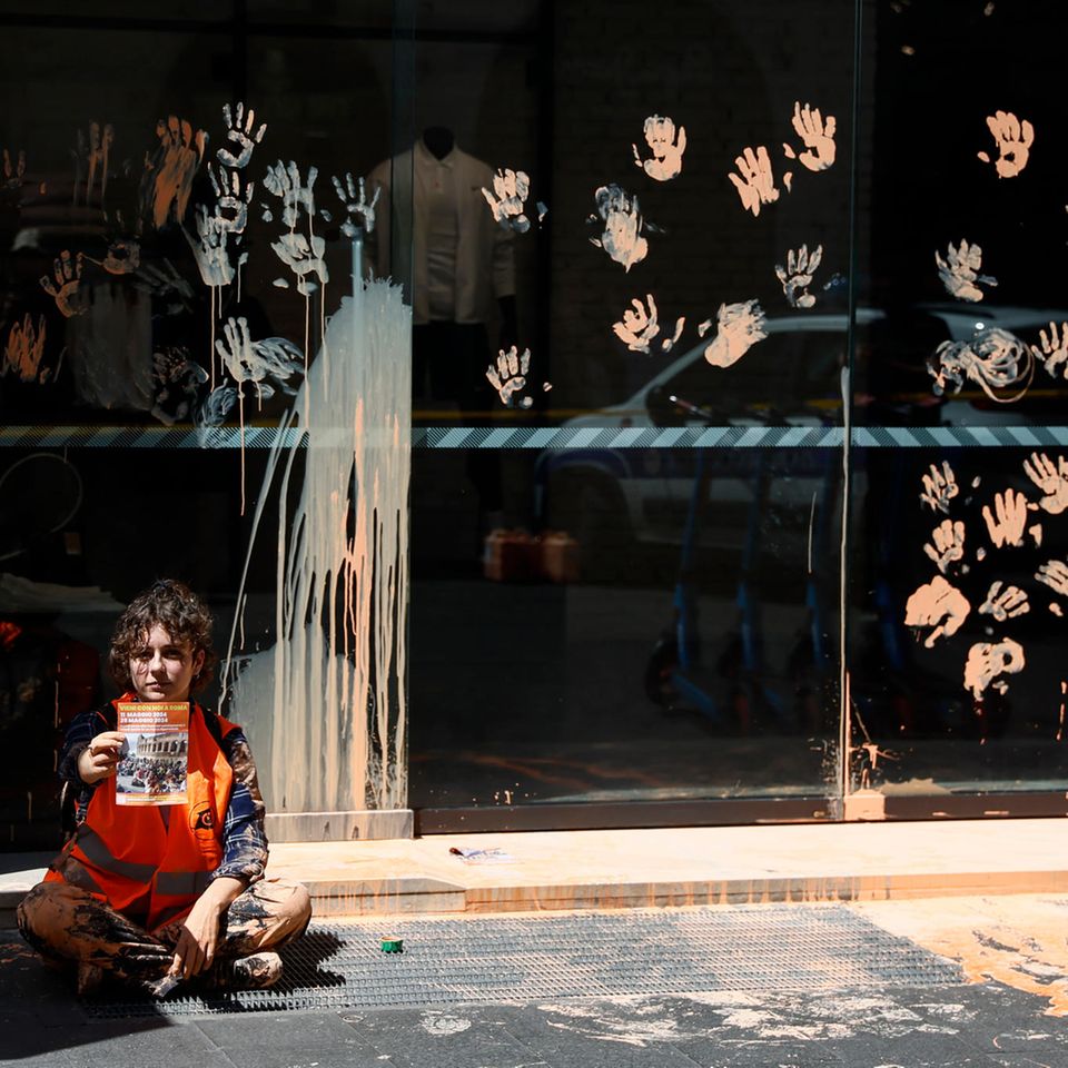 Rom, Italien. Bei einer Protestaktion der Letzten Generation gegen die Firma Nike wurden die Fenster eines Sportgeschäfts mit abwaschbarer Farbe beschmiert. Zusätzlich klebten sich zwei Aktivisten ans Schaufenster.