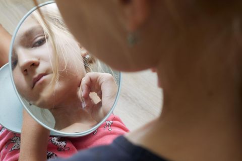 junges Mädchen betrachtet sich im Spiegel