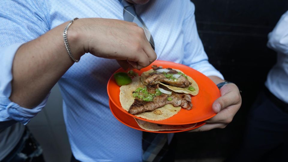 Mexiko-Stadt: Ein Kunde drückt Limettensaft auf seine Tacos am Stand von Tacos El Califa de León Ein Kunde drückt Limettensaft auf seine Tacos am Stand von Tacos El Califa de León
