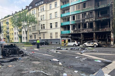 Menschen stehen vor einem ausgebrannten Gebäude in Düsseldorf