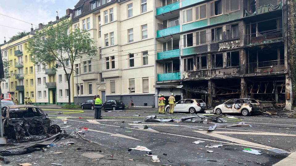 Menschen stehen vor einem ausgebrannten Gebäude in Düsseldorf