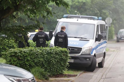 Zwei Polizeibeamte stehen in Schutzwesten vor einem Auto