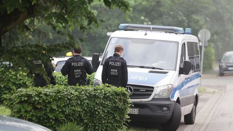 Zwei Polizeibeamte stehen in Schutzwesten vor einem Auto