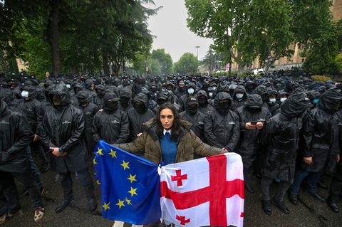 Eine Frau demonstriert in Georgiens Hauptstadt Tiflis mit der Landes- und der EU-Flagge anlässlich der Verabschiedung des Gesetzes zur "Transparenz ausländischer Einflussnahme" am vergangenen Dienstag. Im Hintergrund sperren Polizisten eine Straße ab.
