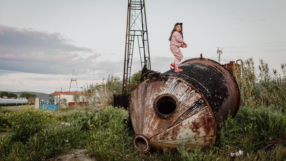 Ein Mädchen klettert auf einem alten Öltank herum