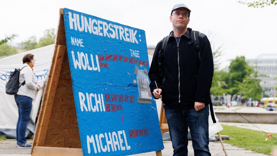 Ein Klimaaktivist steht neben einer Tafel, an der die Mitstreiter ihre Fastentage zählen Ein Klimaaktivist steht neben einer Tafel, an der die Mitstreiter ihre Fastentage zählen