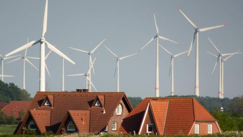 Strom: Wohnhäuser und Windräder hinter dem Deich bei Nessmersiel in Ostfriesland