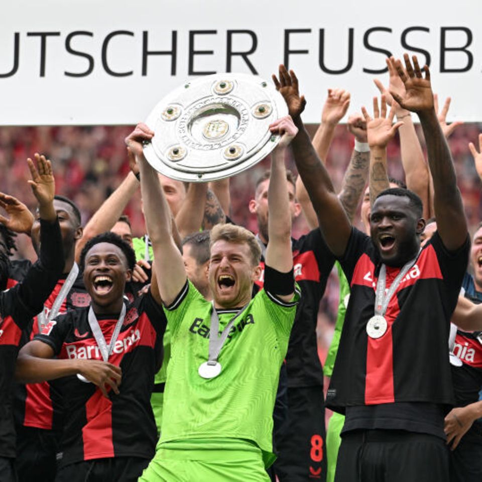 Leverkusen, Deutschland. Bayer 04 ist zum ersten Mal Deutscher Meister. Dem Team von Trainer Xabi Alonso war der Titel schon seit einigen Wochen nicht mehr zu nehmen. Nach dem letzten Spiel gegen den FC Augsburg präsentiert Kapitän Lukas Hradecky den Fans stolz die Schale. Die Werkself blieb die komplette Saison ungeschlagen. 