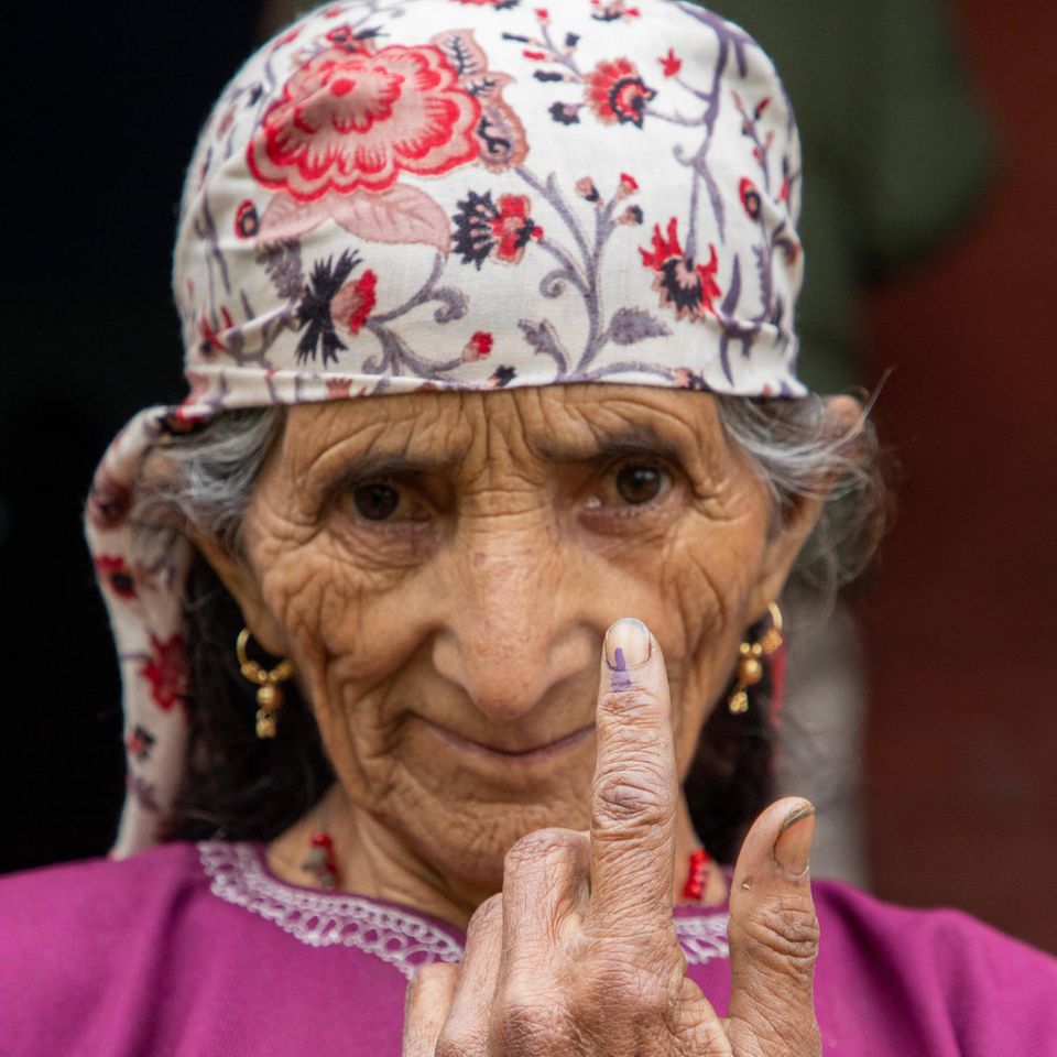Eine Frau aus Kaschmir zeigt ihren mit Tinte beschmierten Finger