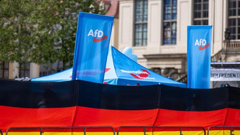 Eine Deutschland Flagge und dahinter ein Wahlstand der AfD