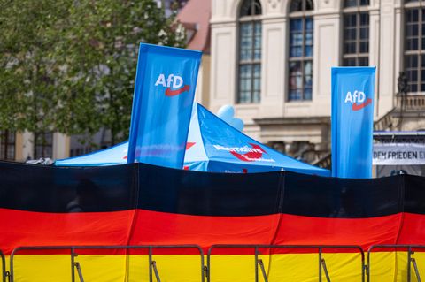 Eine Deutschland Flagge und dahinter ein Wahlstand der AfD