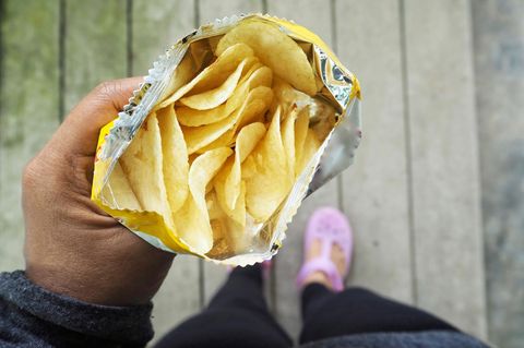 Mann hält eine offene Chipstüte