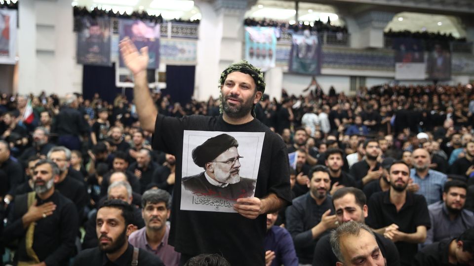 Trauerfeier in Teheran: Teilnehmer halten Plakate des verunglückten Präsidenten Ebrahim Raisi