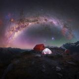 Die Milchstraße über zwei einsamen in einer Bergigen Landschaft aufgebauten Zelten