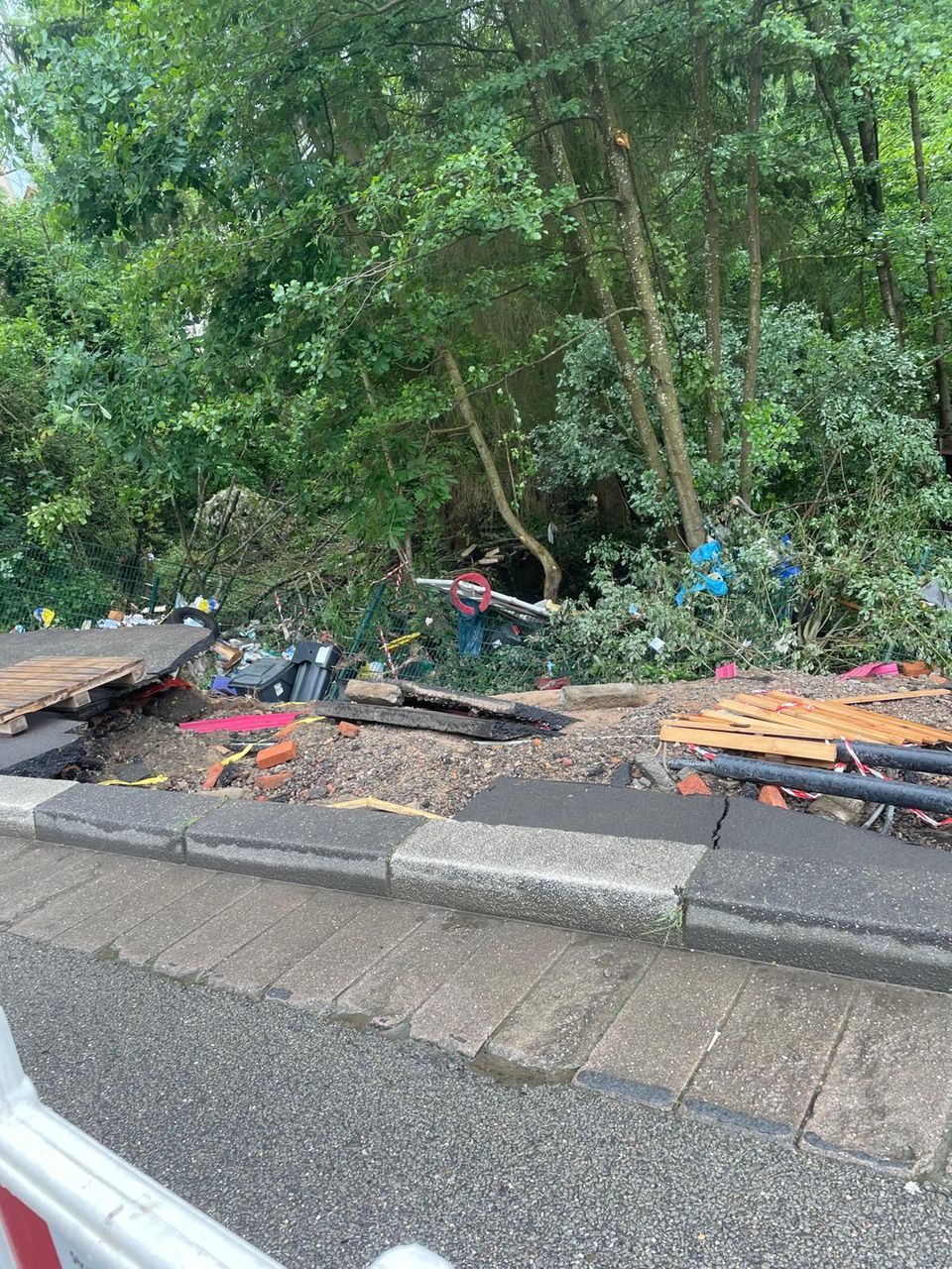 Im Straßengrabenliegen die zerstörten Holzpaletten zwischen kaputten Bäumen.