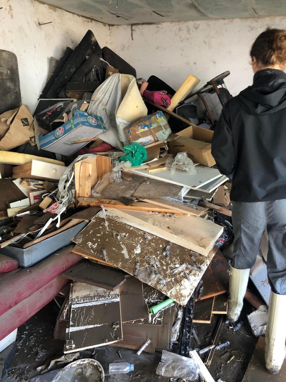 Eine Frau steht in einem Raum. bis an die Decke stapelt sich Sperrmüll.