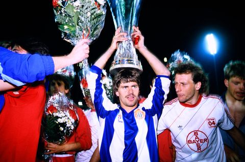 Nach der Siegerehrung trägt Torschütze Falko Götz den Pokal als Krone, daneben ist Kapitän Wolfgang Rolf zu sehen.
