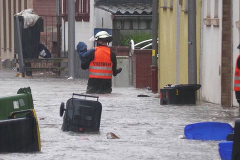 Ein freiwilliger Helfer watet durch das Hochwasser und trägt eine Person.