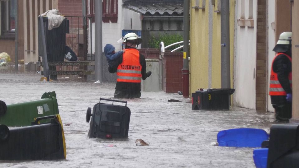 Ein Freiwilliger watet durch das Hochwasser und trägt eine Person.