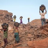 Menschen tragen gesammelte Kohle auf dem Kopf weg