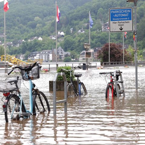 Fahrräder stehen im Wasser auf der überfluteten Promenade an der Mosel