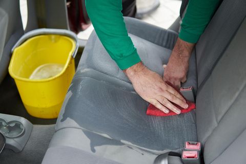 Autositze reinigen: Mann säubert mit einem roten Lappen die Sitzpolster