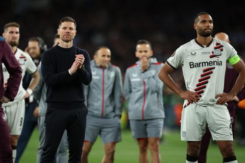 Bayer Leverkusens Trainer Xabi Alonso (l.) und Nationalspieler Jonathan Tah stehen nach dem Spiel enttäuscht auf dem Platz
