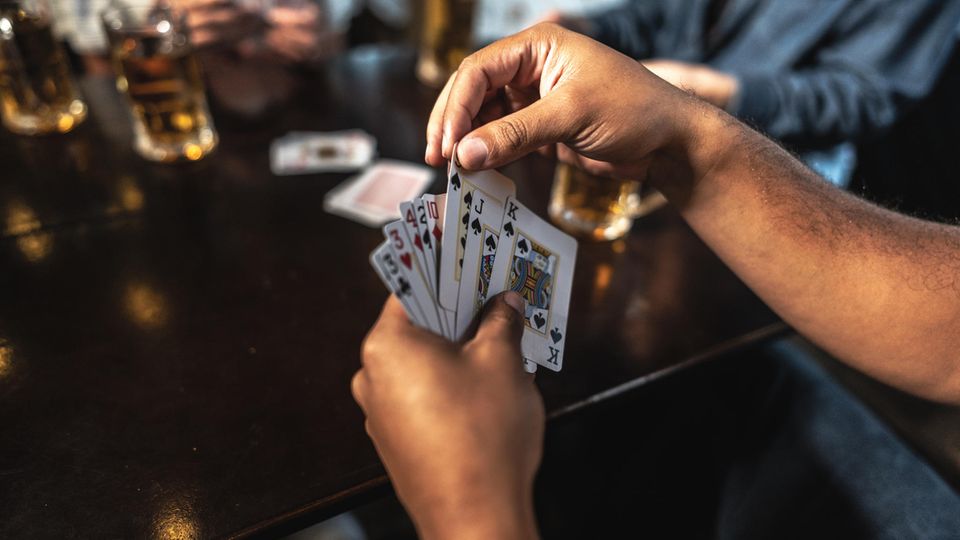 Kartenspiele für Erwachsene: Ein Mann hält Skat-Karten in seiner Hand.
