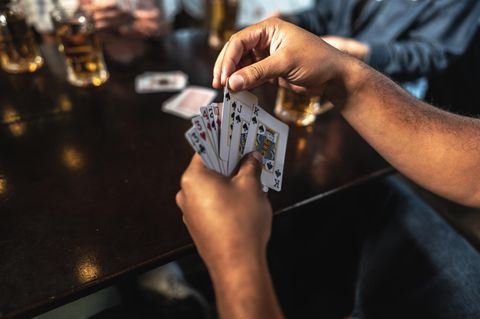 Kartenspiele für Erwachsene: Ein Mann hält Skat-Karten in seiner Hand.
