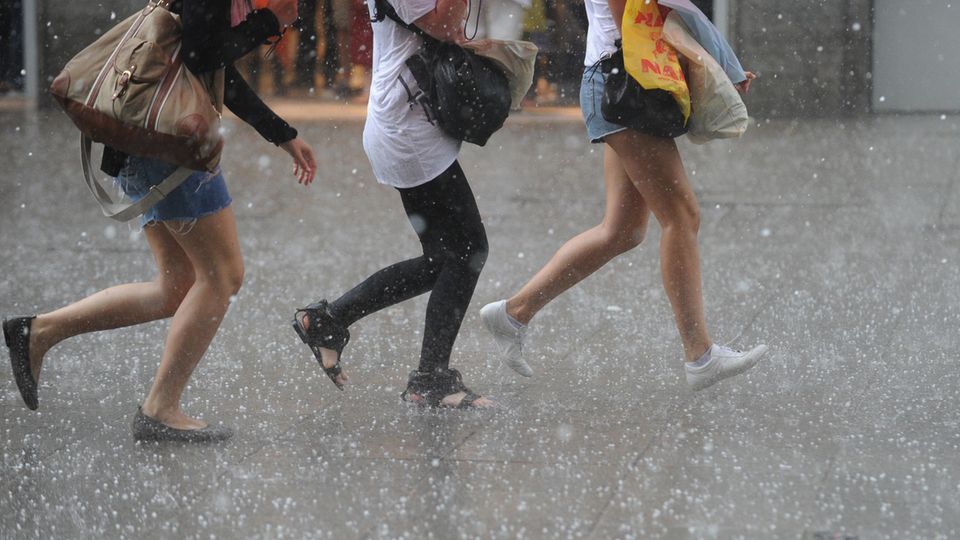 Wetter: Menschen rennen bei Starkregen durch eine Fußgängerzone