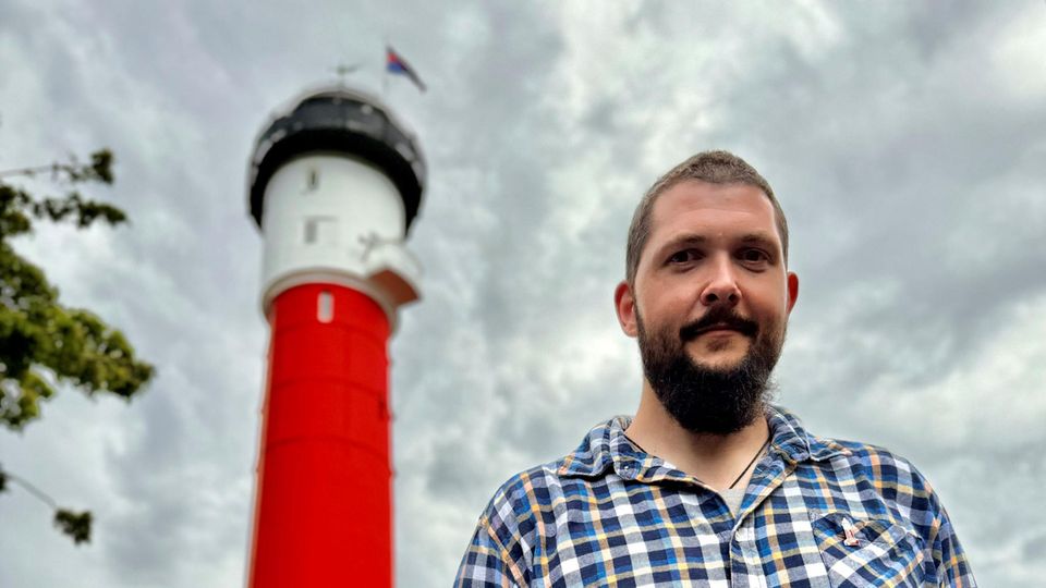 Ein Foto von Daniel Jochheim vor einem Leuchtturm