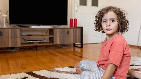 Ein kleiner Junge sitzt schockiert vor dem Fernseher