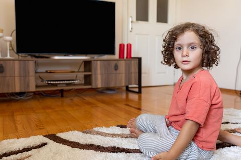Ein kleiner Junge sitzt schockiert vor dem Fernseher