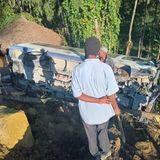 Dorfbewohner stehen neben einem halb verschütteten Auto