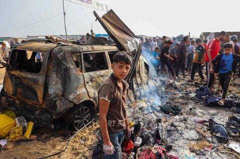 Ein palästinensischer Junge vor einem ausgebrannten Auto in Rafah nach dem Angriff der israelischen Luftwaffe