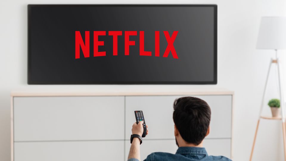 Ein Mann schaltet einen Fernseher ein, der das Netflix-Logo zeigt