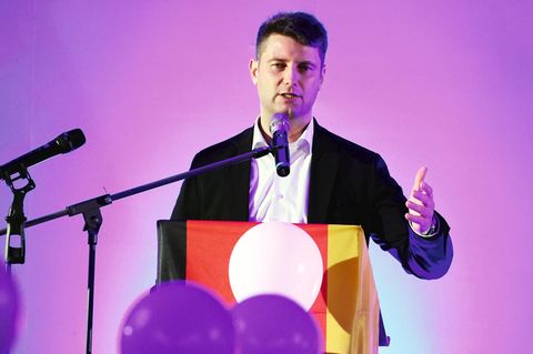 AfD-Politiker René Aust spricht an einem Podium mit Deutschlandfahne in ein Mikrofon