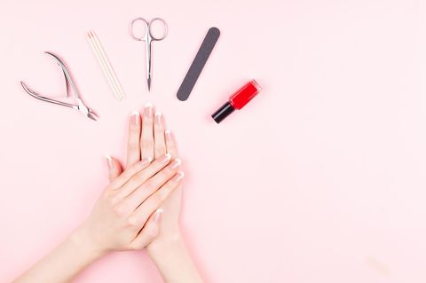 Nagelfeile Handgepäck: Gepflegte Hände und ein Manikür-Set liegen auf einem rosa Tisch.